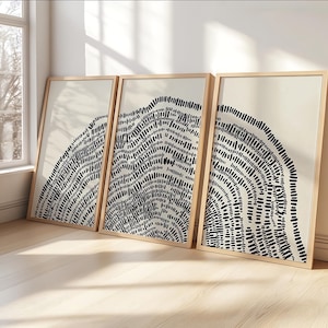 Może przedstawiać: Trzy oprawione abstrakcyjne wydruki artystyczne. Każdy wydruk przedstawia czarno-biały wzór przypominający słoje drzew lub mapę topograficzną. Ramki są w jasnym kolorze drewna, a tło jest neutralne beżowe.