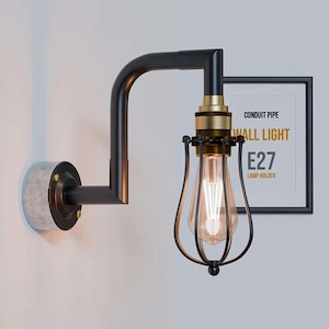 May include: Industrial wall light with a black metal frame and a cage around the bulb. The fixture has a brass bulb holder and a concrete-effect base. A framed sign reads "CONDUIT PIPE WALL LIGHT E27 LAMP HOLDER". The light is designed for an E27 bulb.