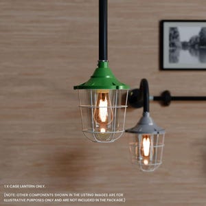 May include: Two industrial pendant lights. One has a green top and the other a grey top, both with clear glass and a cage design. The lights hang from black pipes. The text "1 X CAGE LANTERN ONLY" is visible.