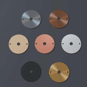 Puede incluir: Colección de siete placas circulares de metal para techo en varios acabados. Las placas incluyen plata, cobre, latón, negro y blanco, cada una con un orificio central y dos orificios más pequeños para el montaje.