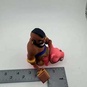Puede incluir: Figura impresa en 3D de un personaje del juego Clash of Clans. El personaje es un hombre de piel oscura con una cresta negra, montado en un cerdo rosa. Sostiene un martillo marr&oacute;n. La figura mide aproximadamente 7.6 cm de altura.
