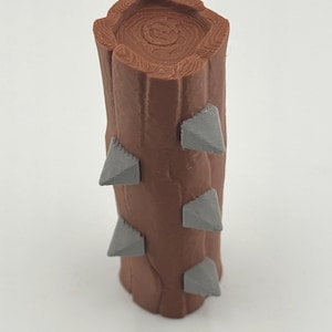 May include: A brown, cylindrical object resembling a tree trunk, featuring a textured surface and a cross-section top. Gray, triangular protrusions are evenly spaced along the sides. The object is likely a decorative item or a component of a larger design.