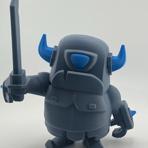 May include: A gray plastic figurine of a knight character with a rounded body, wearing armor with blue horns and a blue visor. The figure holds a gray sword in its right hand and has a small shield on its left arm, featuring a smooth, matte finish.