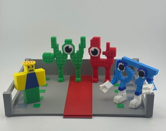 May include: A collection of colorful, pixelated figures, including a yellow and blue character, two green figures, a red figure, and two blue figures with white hands and feet. The figures are arranged on a gray platform with a red pathway.