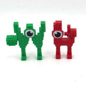May include: Two pixelated figures, one green and one red, stand side-by-side against a white background. The green figure has a blocky arm extended, while both figures have large, round eyes with white and black details. The figures are reminiscent of retro video game characters.