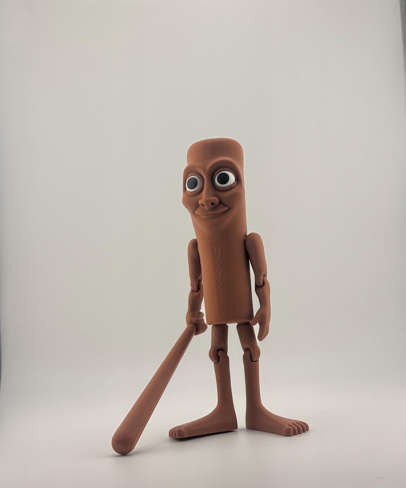 May include: A brown, articulated figurine with a cylindrical body, large eyes, and a smiling expression. The figure is holding a brown, cylindrical object, resembling a baseball bat. The figure has articulated arms and legs, and is standing on a white surface.