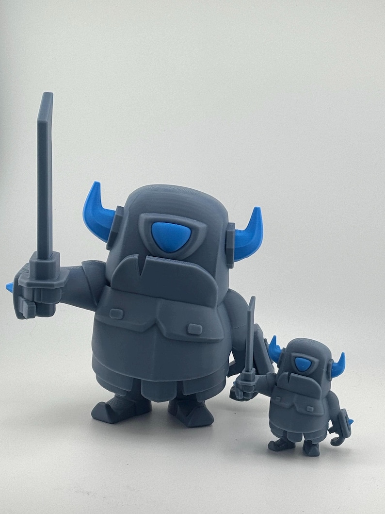 May include: Two gray figurines with blue horns and blue eye visors, each holding a gray sword. The larger figure stands on the left, while the smaller figure stands on the right. Both figures feature a bulky, armored appearance with distinct blue accents.