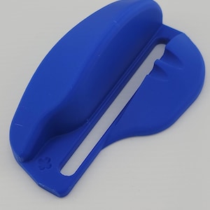 Puede incluir: Una herramienta azul brillante impresa en 3D con un mango curvo y un diseño ranurado. La herramienta tiene un pequeño emblema floral decorativo en un extremo. El objeto probablemente se utiliza para una tarea específica.