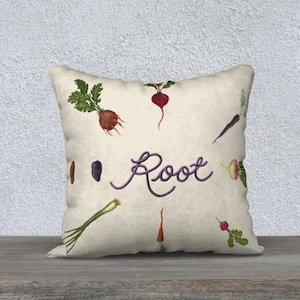 Könnte beinhalten: Ein weißes Kissen mit beigefarbenem Hintergrund, auf dem das Wort "Root" in lila handgeschrieben ist und verschiedene Aquarell-Illustrationen von Wurzelgemüse, darunter Karotten, Radieschen, Rüben und Rote Bete.