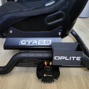 May include: Black racing simulator seat with a black metal frame. The frame has the text "GTR S8 INFINITY" and "OPLITE" in white. A black speaker is mounted below the frame.