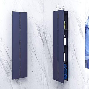 May include: Two dark blue, vertical storage units with shelves, mounted on a white tiled wall. The unit on the right has shelves filled with toiletries and towels.