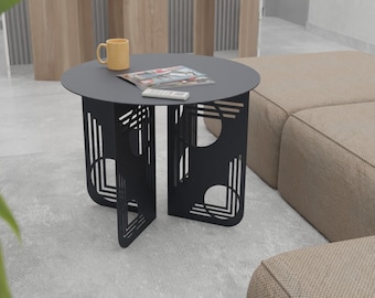 May include: Black metal side table with a geometric design. The table has a round top and a geometric base. A magazine and a mug are on the table.