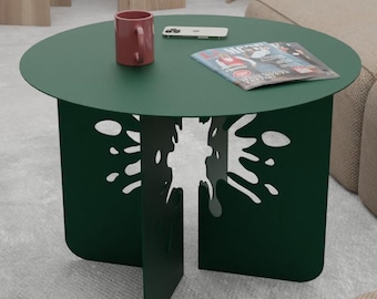 May include: A dark green round coffee table with a unique, abstract design cut into the legs. The table has a smooth, flat surface and is perfect for a living room or den.