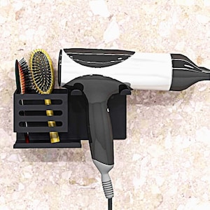 May include: Black hair dryer and two hair brushes mounted on a black wall-mounted holder. The hair dryer has a white body and a black nozzle.