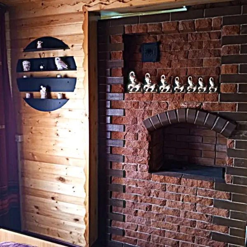 May include: Interior shot of a rustic room with a brick wall and wooden paneling. A series of small owl figurines are displayed on a black, semi-circular shelf. The brick wall features a small arched opening and a row of decorative figurines.