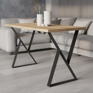 May include: A rectangular wooden table with a light brown surface and black metal legs. The legs have an X-shaped design. Two white vases and two small white bowls are on the table. The table is in a living room setting.