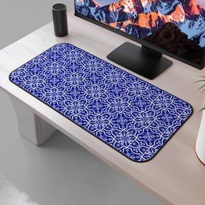 May include: Blue and white patterned mouse mat with a geometric design. The mouse mat is on a wooden desk with a computer monitor and a speaker.