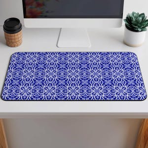 May include: Blue and white patterned mouse mat with a geometric design. The mouse mat is on a white desk.