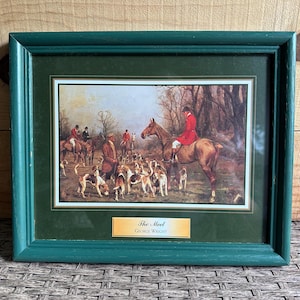 Peut inclure: Une impression encadrée intitulée "The Meet" par George Wright, représentant une scène de chasse. L'œuvre montre des cavaliers à cheval, des chiens et des personnages en tenue de chasse. Le cadre est vert sarcelle foncé.