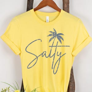 May include: Yellow short-sleeved t-shirt with a palm tree graphic and the text "Salty" in a distressed font.