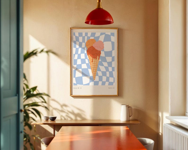 May include: A framed art print featuring an ice cream cone with three scoops in shades of orange and pink. The background is a blue and white checkered pattern. The print is displayed on a beige wall in a room with a red light fixture.