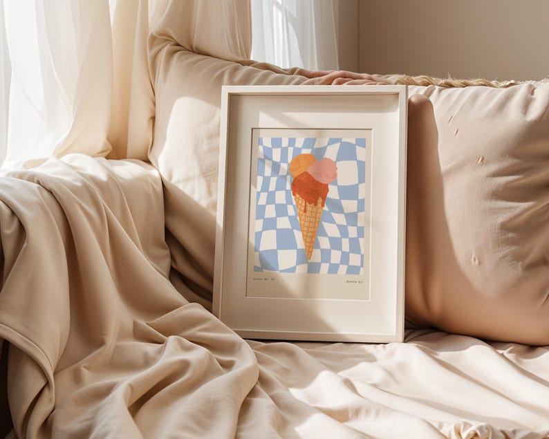 May include: A framed art print featuring an ice cream cone with three scoops in shades of orange and pink. The cone is set against a blue and white checkered background. The frame is white.