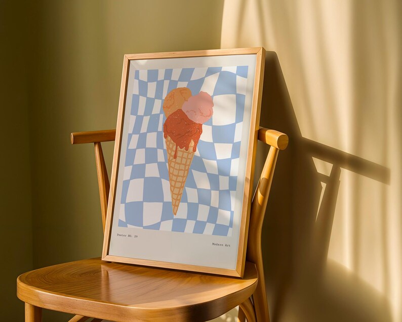 May include: A framed art print featuring an ice cream cone with three scoops in shades of orange and pink. The background is a blue and white checkered pattern. The print is displayed on a wooden chair.