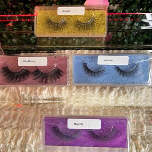K&ouml;nnte beinhalten: Vier transparente Plastikboxen mit verschiedenen Hintergrundfarben und falschen Wimpern darin. Die Boxen sind mit "Spoiled", "Play Bunny", "Jasmine" und "Majesty" beschriftet.