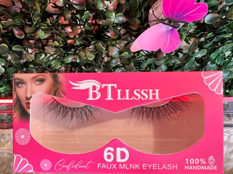 K&ouml;nnte beinhalten: Rosa Verpackung f&uuml;r 6D Faux Mink Wimpern mit dem Markennamen "BTLLSSH" und dem Text "100% HANDMADE" unten. Die Wimpern sind durch ein transparentes Plastikfenster sichtbar.