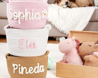 Könnte beinhalten: Drei übereinander gestapelte Aufbewahrungskörbe aus Seil mit personalisierten Namen: Sophia, Ela und Pineda. Die Körbe sind rosa, weiß und braun.
