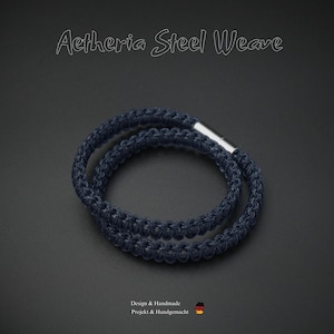 Könnte beinhalten: Aetheria Steel Weave Armband. Ein dunkelblaues, gewebtes Armband mit Silberverschluss. Das Armband besteht aus einem dicht gewebten Material, und der Text "Aetheria Steel Weave" befindet sich oben im Bild.