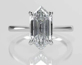 May include: A silver ring featuring a large, clear, emerald-cut gemstone. The gemstone is set with four prongs and has a distinctive, geometric shape. The ring's band is thin and polished, reflecting light. The ring is displayed on a reflective surface.