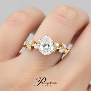 Vintage inspired 2 Ct pear cut moissanite engagement ring featuring leaf vine diamond band in 14K yellow gold, perfect for nature lovers and brides seeking a unique floral bridal ring.