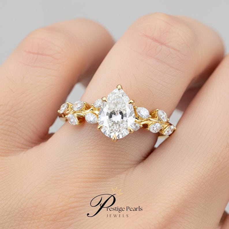 Vintage inspired 2 Ct pear cut moissanite engagement ring featuring leaf vine diamond band in 14K yellow gold, perfect for nature lovers and brides seeking a unique floral bridal ring.