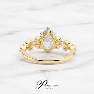 Beautiful 2 Ct pear moissanite engagement ring crafted in 14K yellow gold with leaf and vine diamond details, a nature inspired vintage bridal ring for brides who love elegant organic designs.