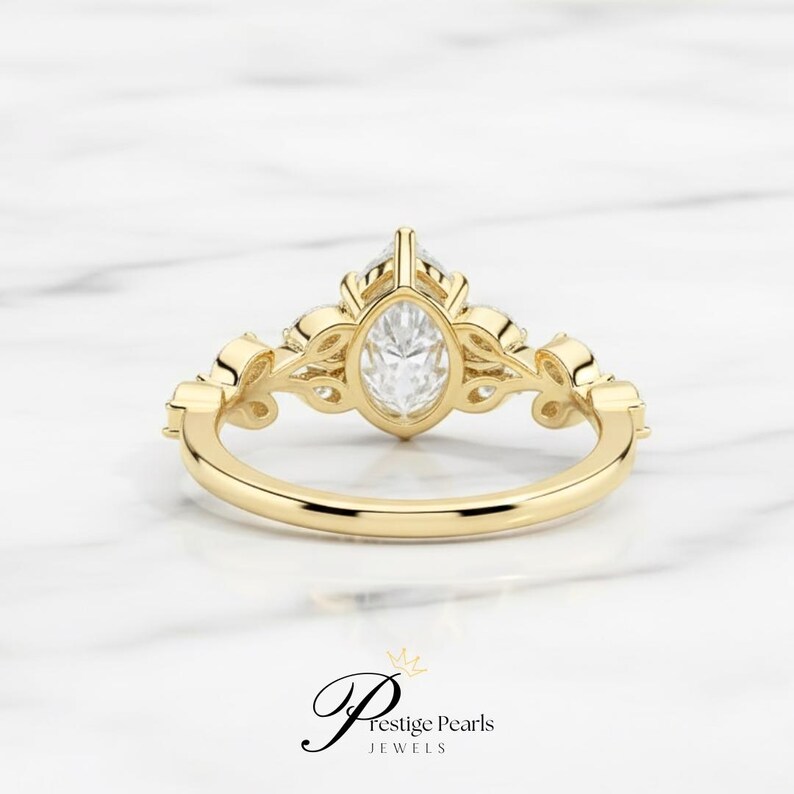 Beautiful 2 Ct pear moissanite engagement ring crafted in 14K yellow gold with leaf and vine diamond details, a nature inspired vintage bridal ring for brides who love elegant organic designs.