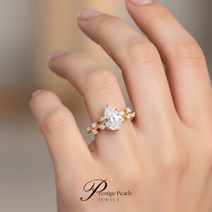 Handcrafted 2 Ct pear cut moissanite ring in yellow gold with leaf pattern diamond accents, unique floral engagement ring inspired by nature and vintage artistry, perfect for weddings.