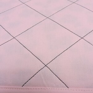 Peut inclure: Gros plan sur un tissu rose avec un motif en losange cousu avec du fil noir.