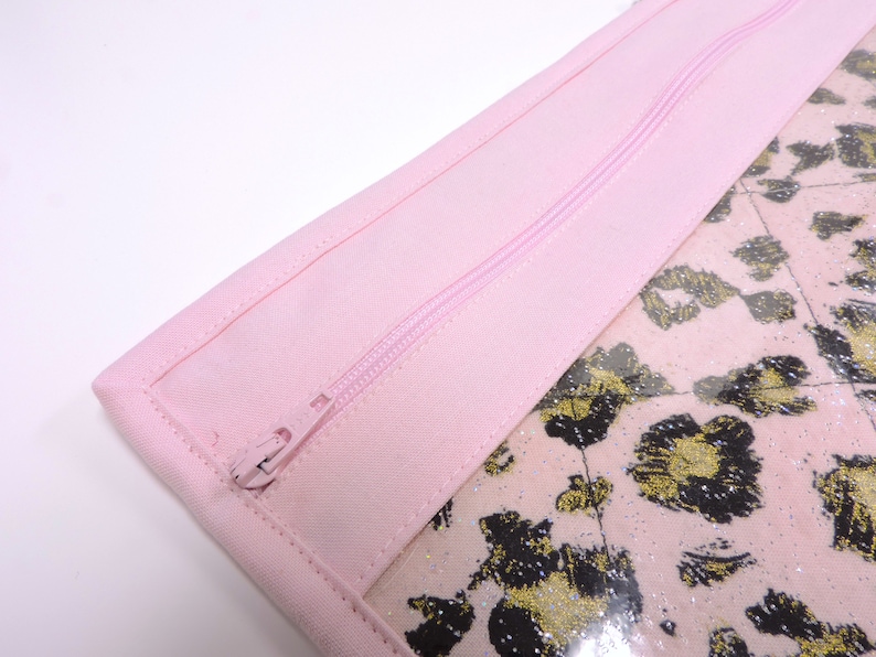 Peut inclure: Une pochette zipp&eacute;e rose avec une fen&ecirc;tre transparente qui r&eacute;v&egrave;le un tissu l&eacute;opard rose et or.