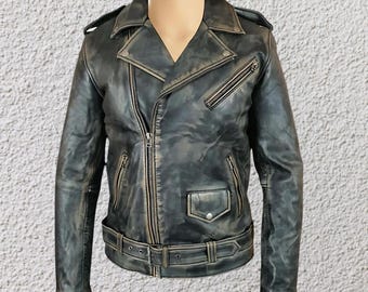 May include: A distressed, dark gray leather jacket with a classic biker style. Features include an asymmetrical zipper, multiple zippered pockets, a snap-down lapel, and a belted waist. The jacket has a worn, vintage look.