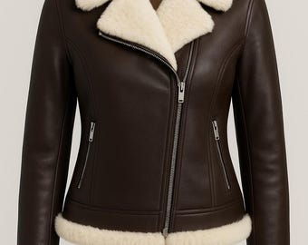 Può includere: Giacca in pelle marrone con colletto, polsini e fodera in montone color crema. La giacca presenta una chiusura con zip diagonale, due tasche con zip e un classico stile aviatore.