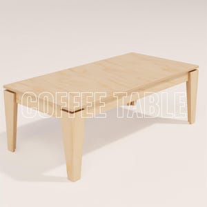May include: A light-colored wooden coffee table with a rectangular top and four sturdy legs. The table has a simple, modern design and the text "COFFEE TABLE" is displayed across the top.