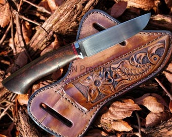 May include: A brown leather knife sheath with a floral design. The sheath has a stitched edge and a belt loop. A knife with a brown wooden handle and a silver blade is inside the sheath.