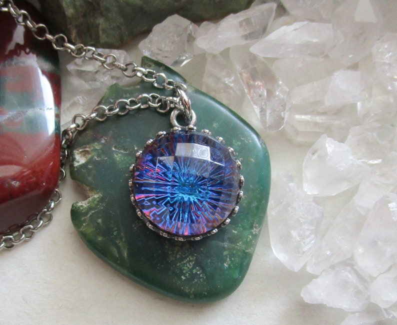 May include: A silver chain necklace with a round pendant featuring a blue and purple iridescent glass cabochon set in a silver bezel.