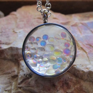 May include: A silver necklace with a round pendant containing iridescent glass beads.