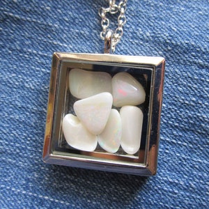 May include: A silver pendant necklace with a clear glass locket containing several white opal stones.