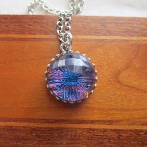 May include: A silver chain necklace with a round iridescent blue glass pendant with a faceted design.