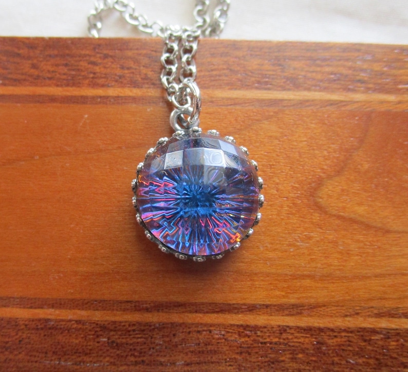 May include: A silver chain necklace with a round iridescent blue glass pendant with a faceted design.