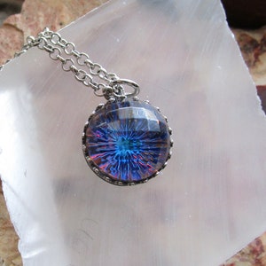 May include: A silver chain necklace with a round pendant featuring a blue and purple iridescent glass design with a silver bezel.