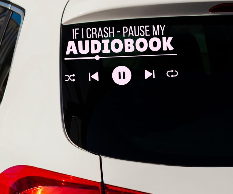 May include: White vinyl car decal with the text "IF I CRASH - PAUSE MY AUDIOBOOK" above a media player interface. The interface includes pause, rewind, fast forward, and shuffle icons. The decal is applied to a car window.